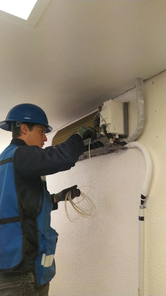 Técnico instalando unidad de aire acondicionado en pared