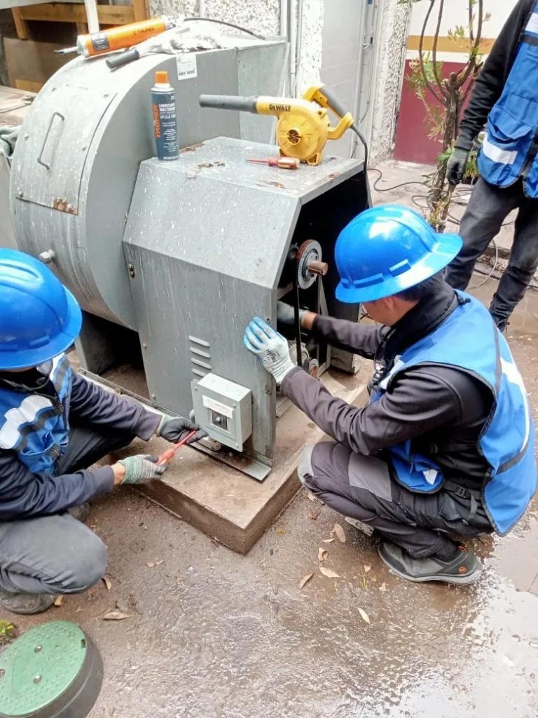 Técnicos con cascos azules realizando mantenimiento a maquinaria industrial